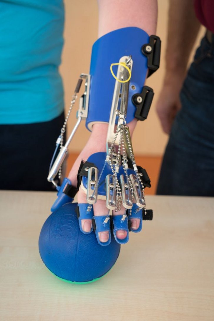 Hand greift mit SAEBO-Orthese nach Ball