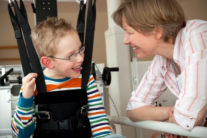 Junge im Lokomat mit Therapeutin