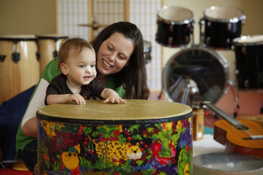 Kleinkind trommelt mit Therapeutin
