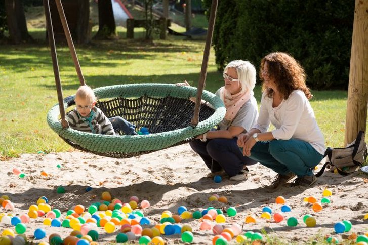 Junge in Nestschaukel mit Mutter