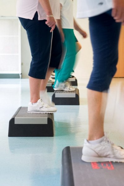Patienten trainieren mit Stepper in orthopädischer Reha - Nahaufnahme der Unterkörper