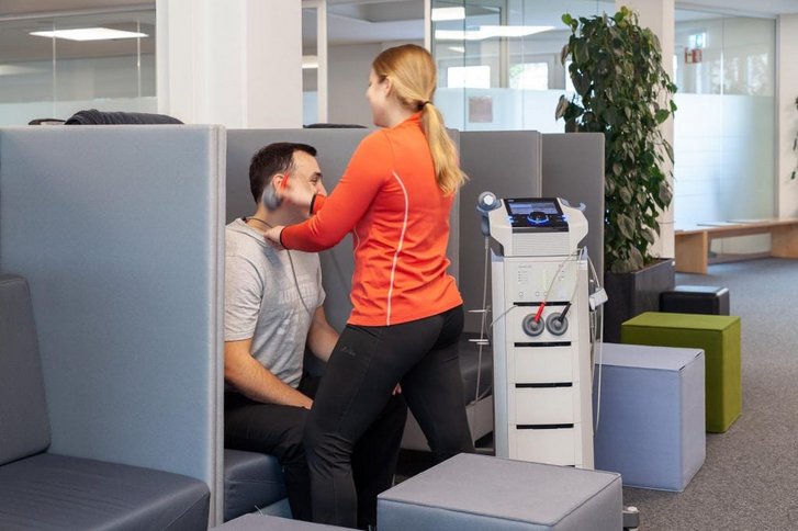 Eine Physiotherapeutin bei der Anwendung einer Elektrotherapie am Patient in der Physiotherapie Abteilung Karlsruhe