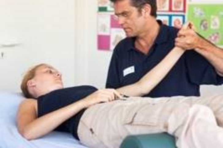 Eine auf dem Ruecken liegende Patientin bekommt eine PNF Behandlung in der Physiotherapie Abteilung des VAMED Rehazentrum Karlsruhe