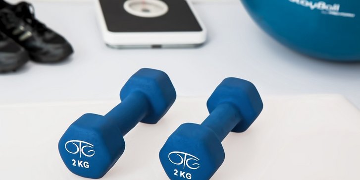 Ausschnitt verschiedener Fitnessgeraete wie Hanteln, Schuhe, Trainingsball und Waage.