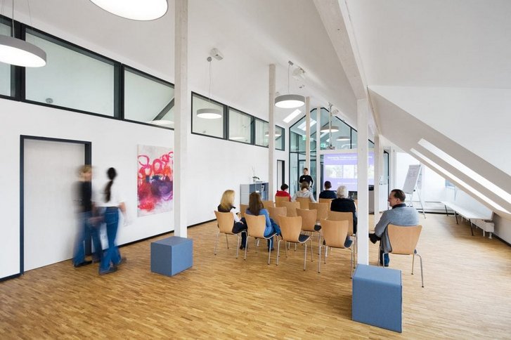 Blick von hinten in den teilweise mit Patienten gefuellten Vortragsraum des VAMED Rehazentrums Karlsruhe