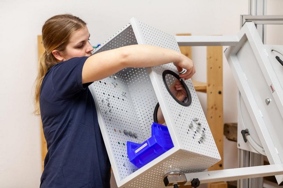 Patientin trainiert Anschrauben ohne Sichtkontrolle in Einzeltherapie im Rahmen der Eine Patientin arbeitet in der Hocke vor einer Wand im Rahmen der medizinisch beruflich orientierten Rehabilitation des VAMED Rehazentrums Karlsruhe