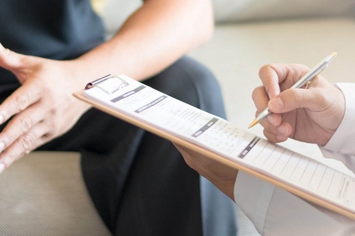 Nahaufnahme von Haenden die einen Arzt beim Ausfuellen eines Antrags zeigen