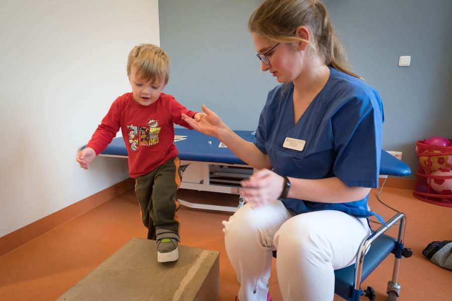 Junge klettert an Hand von Therapeutin