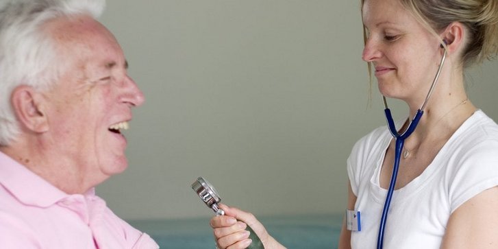 Lachender Patient bekommt von Aerztin Blutdruck gemessen